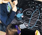 Magic Blackboard being used by children to draw with chalk &amp; chalk markers